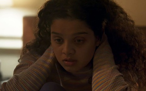 Danielle Olímpia caracterizada como Karina; ela está com lágrimas nos olhos e o semblante abalado em cena de Travessia