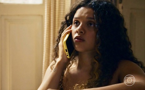 A atriz Danielle Olímpia está falando pelo celular em cena da novela Travessia como a personagem Karina