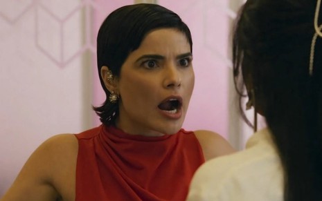 Vanessa Giácomo está com a boca aberta e usa blusa vermelha em cena de Travessia na qual contracena como Dandara Mariana