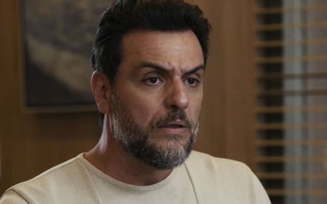 Rodrigo Lombardi caracterizado como Moretti; ator tem as sobrancelhas franzidas e o rosto comprimido em cena de Travessia