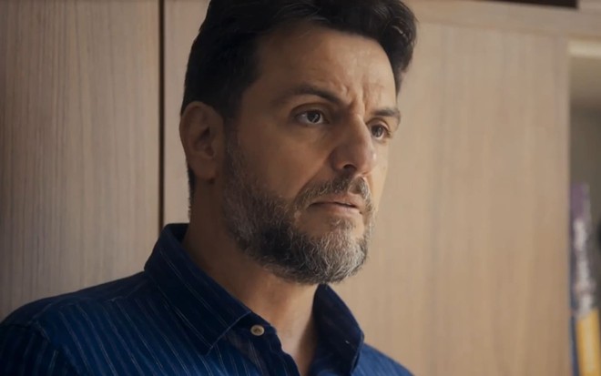 Rodrigo Lombardi caracterizado como Moretti; ator tem as sobrancelhas franzidas e o rosto comprimido em cena de Travessia