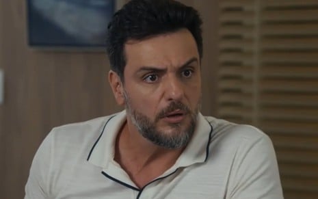 Rodrigo Lombardi caracterizado como Moretti; ator tem os olhos arregalados e o semblante indignado em cena de Travessia