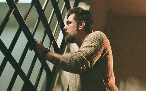O ator Rodrigo Lombardi está caracterizado como Moretti em cena em uma cela na novela Travessia