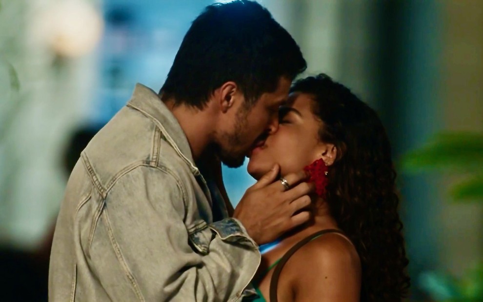 Romulo Estrela beija Clara Buarque com as mãos na altura do pescoço dela em cena noturna da novela Travessia