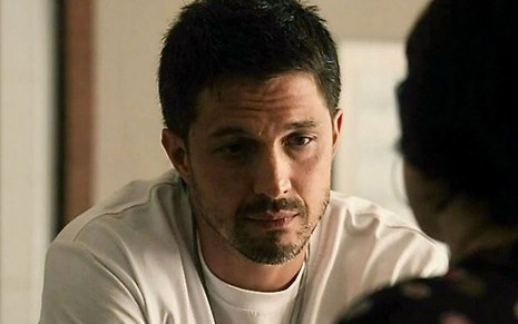 O ator Romulo Estrela está cabisbaixo em cena da novela Travessia como o personagem Oto