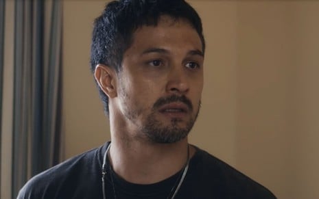 O ator Romulo Estrela com expressão séria em cena de Travessia