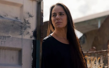 Claudia Marzo caracterizada como Pilar; ela segura uma arma e tem o semblante firme em cena de Travessia