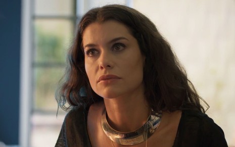 Bárbara (Alinne Moraes) usa roupa preta e colar; ela aparenta estar com raiva em cena de Um Lugar ao Sol