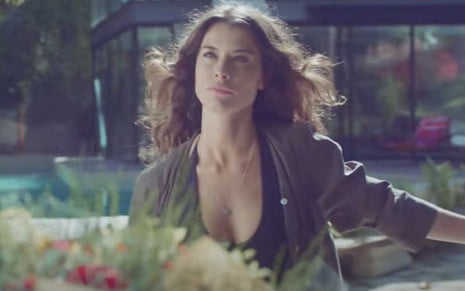 A atriz Alinne Moraes caracterizada como Bárbara em cena externa, em um jardim, de Um Lugar ao Sol