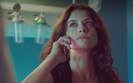 Bárbara (Alinne Moraes) está sentada em cama de hospital; ela chora falando ao telefone em cena de Um Lugar ao Sol
