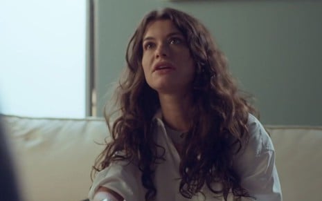 Bárbara (Alinne Moraes) está sentada em recepção de hospital em cena de um Lugar ao Sol