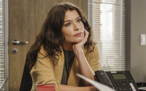 Bárbara (Alinne Moraes)  está sentada em escritório da Redentor em cena de Um Lugar ao Sol