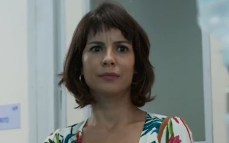 Lara (Andréia Horta) está em pé em corredor da Redentor; ela usa uma blusa estampada em cena de Um Lugar ao Sol