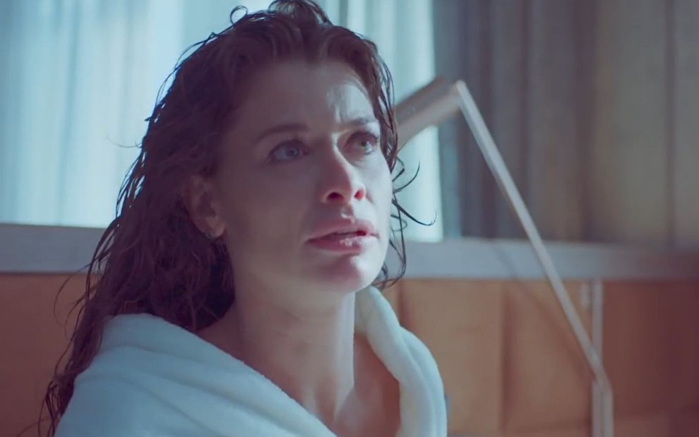 Alinne Moraes em cena de Um Lugar ao Sol: em close, atriz está de roupão e olha com cara de choro para alguém