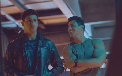 Renato e Christian, ambos interpretados por Cauã Reymond, estão lado a lado em posto de gasolina em cena de Um Lugar ao Sol