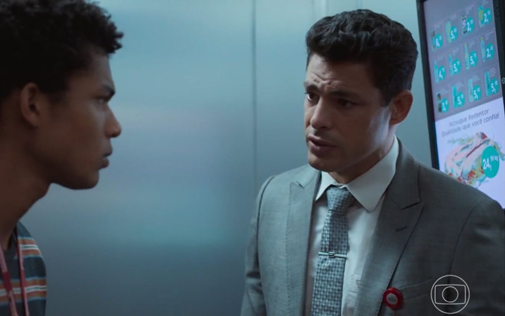 Christian (Cauã Reymond) e Ravi (Juan Paiva) estão em elevador em cena de Um Lugar ao Sol