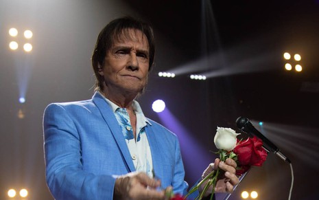 Roberto Carlos, de cara fechada, distribui rosas brancas e vermelhas ao fim de um show