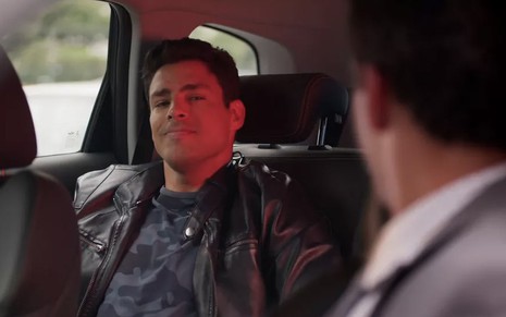 O ator Cauã Reymond como o Renato dentro de um carro, com um sorriso cínico, em cena de Um Lugar ao Sol