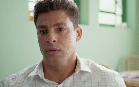 O ator Cauã Reymond em cena como Christian, com expressão séria e triste e camisa branca em Um Lugar ao Sol