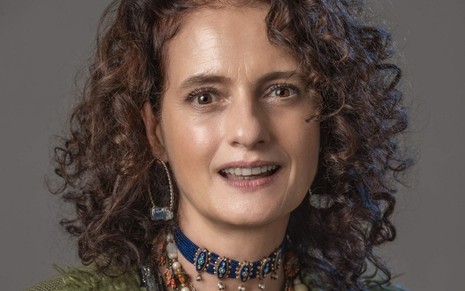 Denise Fraga está caracterizada como a personagem Júlia de Um Lugar ao Sol, ela usa vários colares no pescoço