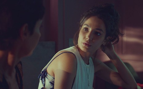 Cecília (Fernanda Marques) está sentada em cama em cena de Um Lugar ao Sol