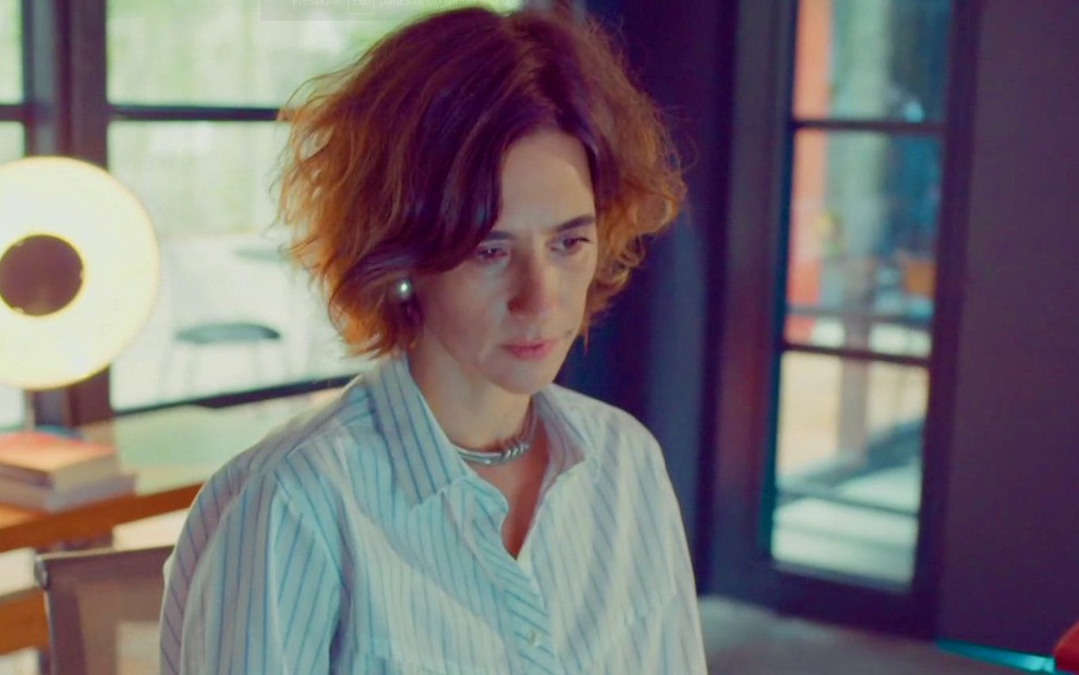 A atriz Mariana Lima está cabisbaixa e simula tristeza em cena de Um Lugar ao Sol, novela em que interpreta Ilana