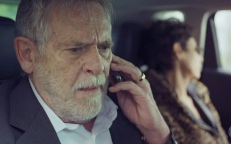 O ator José de Abreu segura celular em gravação de cena de Um Lugar ao Sol em que Andrea Beltrão está ao seu lado desfocada