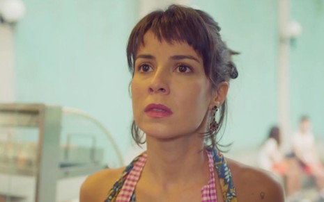 Lara (Andréia Horta) está com avental em cantina em cena de Um Lugar ao Sol