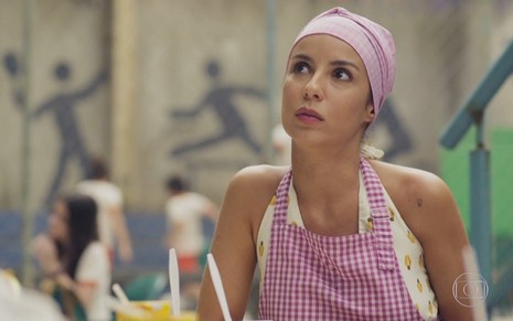 A atriz Andréia Horta em cena da novela Um Lugar ao Sol no qual está com avental e touca de cozinheira de escola