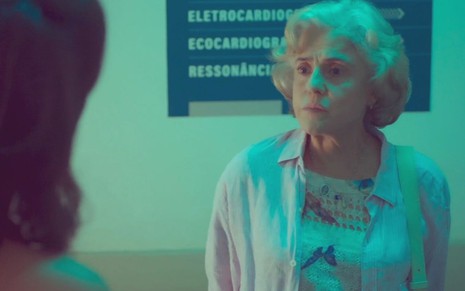 Noca (Marieta Severo) está parada em pé em corredor de hospital em cena de Um Lugar ao Sol