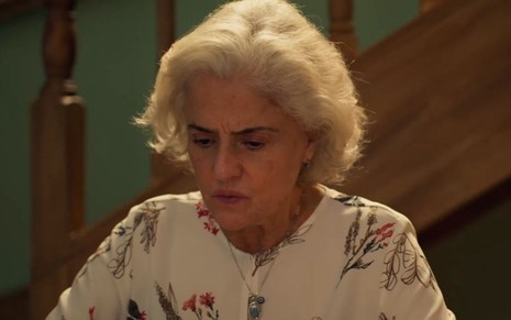 Marieta Severo como Noca em cena de Um Lugar ao Sol: atriz está sentada e olha para baixo com insegurança