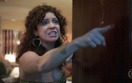 Renata Gaspar como Stephany em cena de Um Lugar ao Sol: atriz está em close, com cabelos cacheados, batom vermelho e grita com o dedo em riste
