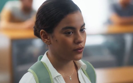 Bella Campos caracterizada como Jenifer; ela tem o semblante sério e surpreso em cena de Vai na Fé