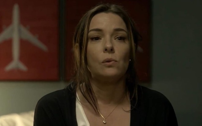 Regiane Alves caracterizada como Clara; ela tem os cabelos presos e não usa maquiagem. Atriz veste casaco e camiseta gastos em cena da novela.