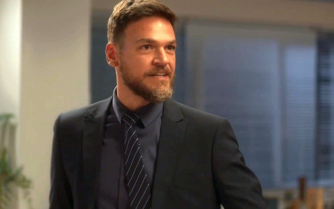 Theo (Emilio Dantas) de terno e gravata em cena de Vai na Fé