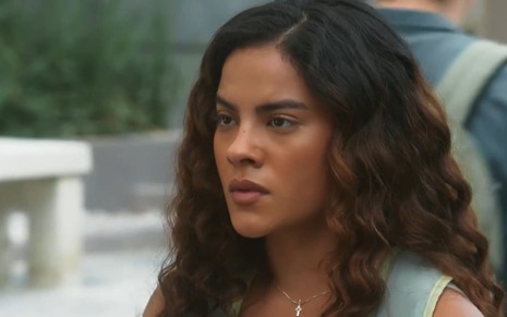 Bella Campos caracterizada como Jenifer; ela tem o semblante apreensivo em cena de Vai na Fé