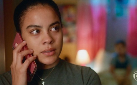 A atriz Bella Campos grava cena de Vai na Fé com cabelo preso e segurando celular próximo à orelha como Jenifer