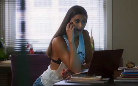 Érika (Leticia Salles) fala al telefone sentada diante de uma messa de escritório em cena de Vai na Fé