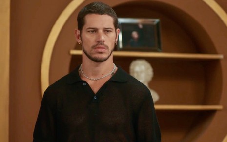 José Loreto usa blusa preta e está com expressão séria em cena da novela Vai na Fé como Lui Lorenzo