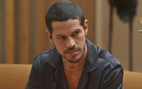 José Loreto caracterizado como Lui Lorenzo em Vai na Fé; ele está com uma camisa preta e tem um olhar sedutor em cena da novela