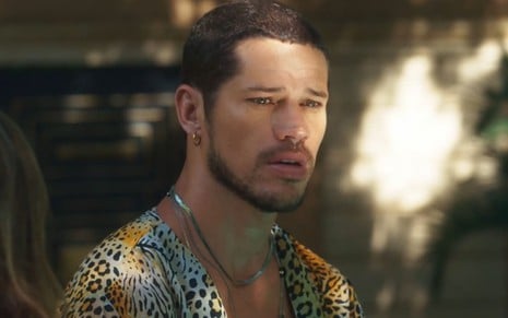 José Loreto caracterizado como Lui Lorenzo em Vai na Fé; ele está com uma camisa estampada aberta e parece abalado em cena da novela