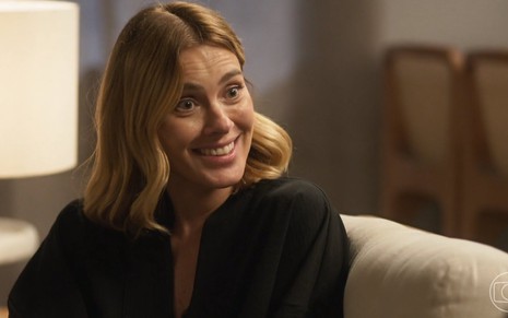 A atriz Carolina Dieckmann está sorrindo e usa blusa preta em cena da novela Vai na Fé como Lumiar