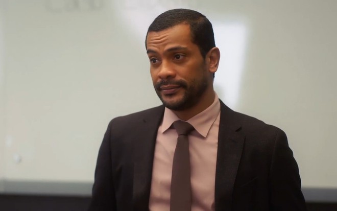 Ben (Samuel de Assis) come expressão resignada em cena de Vai na Fé