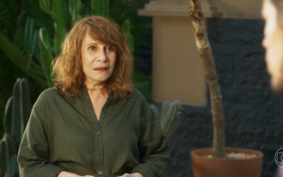 A atriz Renata Sorrah está séria e usa uma camisa verde em cena da novela Vai na Fé como a personagem Wilma