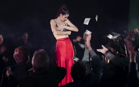 Camila Queiroz grava em cima de palco com calça vermelha e retirando o sutiã, como Angel de Verdades Secretas 2
