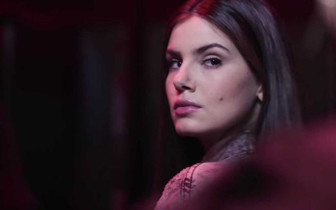 A atriz Camila Queiroz vira a cabeça como se fosse chamada por alguém como a Angel em cena de Verdades Secretas 2
