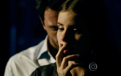 Camila Queiroz grava cena de Verdades Secretas com a mão na boca, enquanto Rodrigo Lombardi está atrás dela