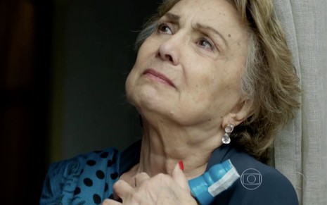 A personagem Fábia (Eva Wilma) olha triste para o céu enquanto segura uma garrafa de bebida alcoólica na novela Verdades Secretas, da Globo