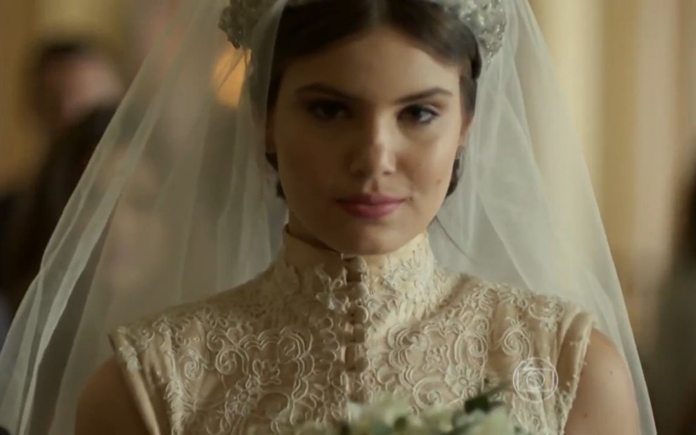 A atriz Camila Queiroz vestida de noiva com expressão misteriosa em cena como Angel na primeira versão de Verdades Scretas