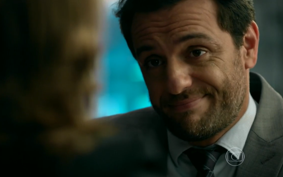 Rodrigo Lombardi usa terno e sorri em cena caracterizado como Alex em Verdades Secretas